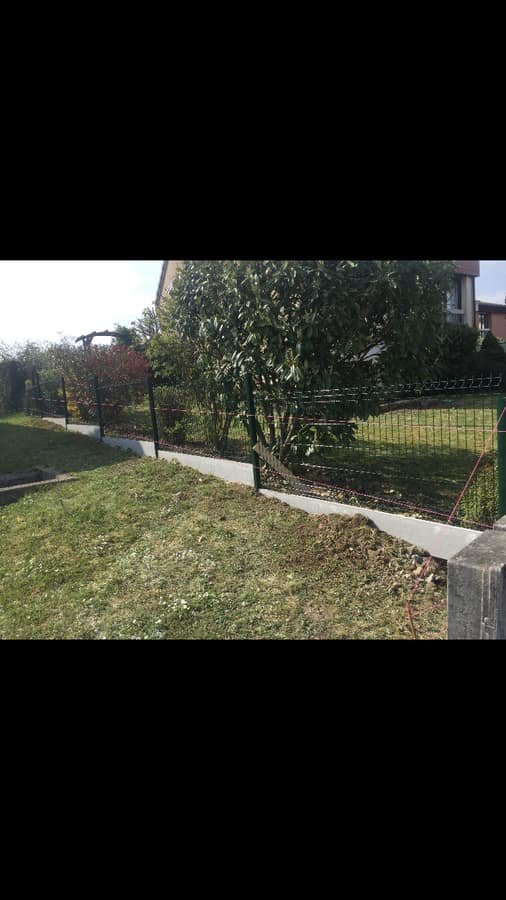 Pose en cours d'une cloture rigide verte sur longrines beton avec cordeau d'alignement