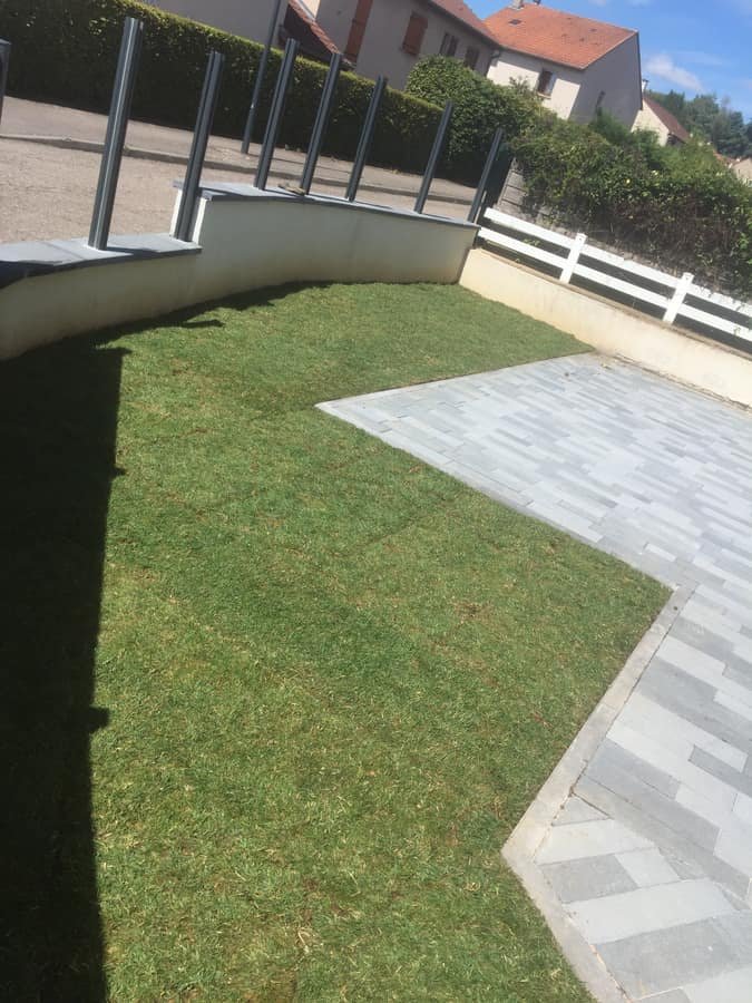 Pelouse en rouleau posee autour d'une terrasse en dalles claires