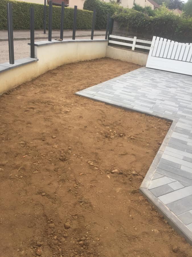 Terrain decape et nivele pret a recevoir le gazon, le long d'une terrasse dallee