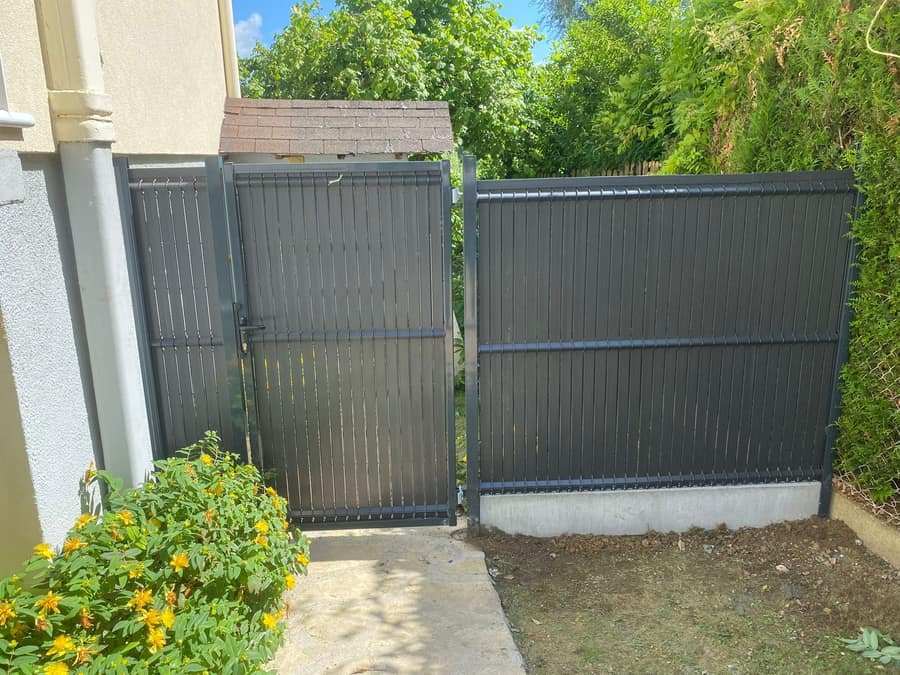 Portillon anthracite et panneaux rigides occultants installes sur le cote d'une maison